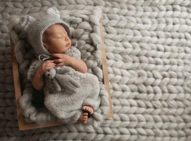 Free photo tiny baby in grey clothes sleeps on woolen blanket