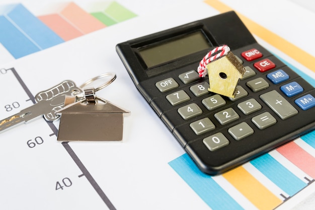 Tiny birdhouse on calculator and house key chain on graph