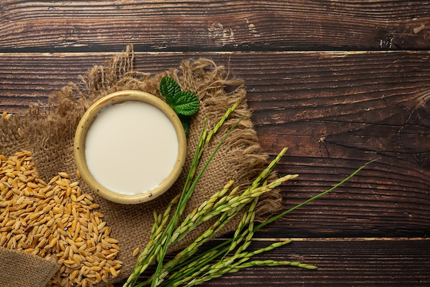 Tiny bowl of rice milk with rice plnt and rice seed put on wooden floor