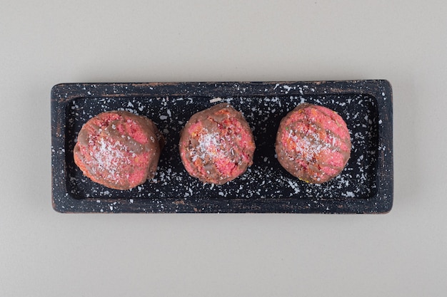 Tiny cakes on a black tray on marble background.