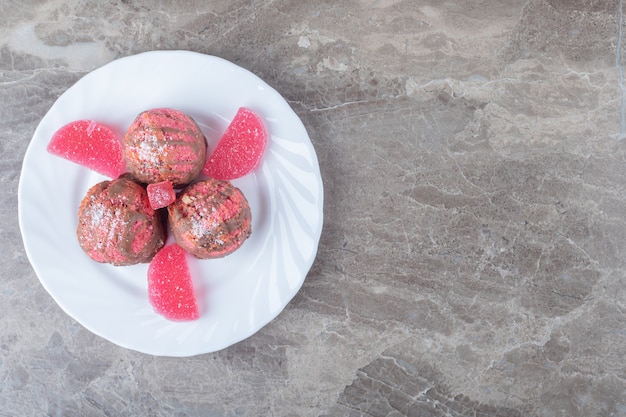 Tiny cakes and marmelades on a platter on marble surface