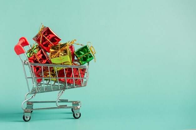 Tiny gift boxes put in mini cart on light green floor