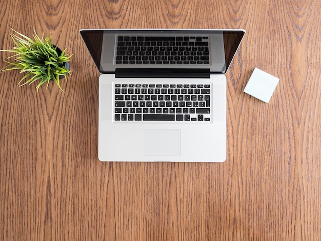 Free photo tip view of businessman desk with a laptop and a pot of grass. flatlay  image