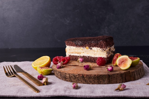 Tiramisu cake decorated with dried flowers and fruits on round wooden board. 