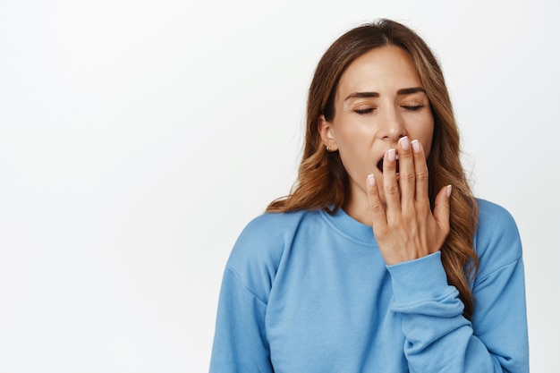 Foto gratuita donna adulta stanca che sbadiglia e copre la bocca aperta con la mano