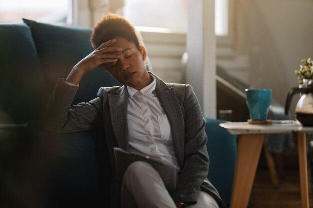 Tired African American entrepreneur having a headache while working on business reports at home