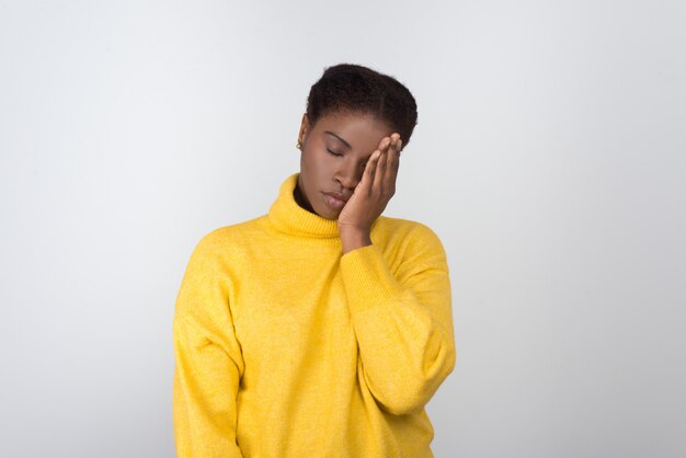 Tired African American woman holding hand on face