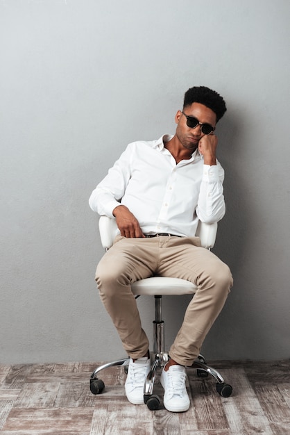 Tired afro american man in sunglasses sitting in a chair