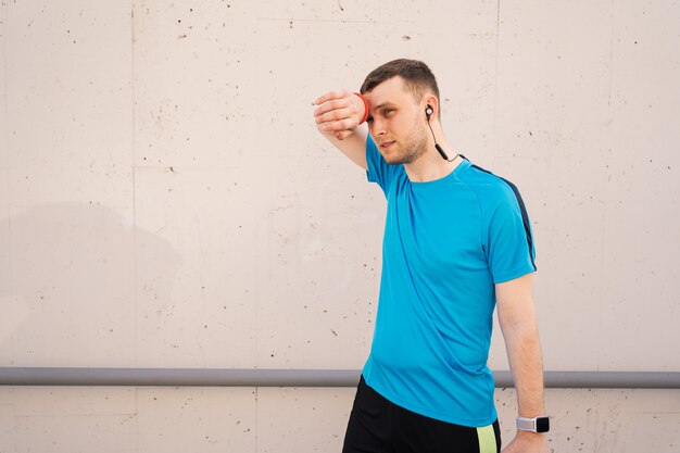 Tired athletic man wiping sweat on his forehead