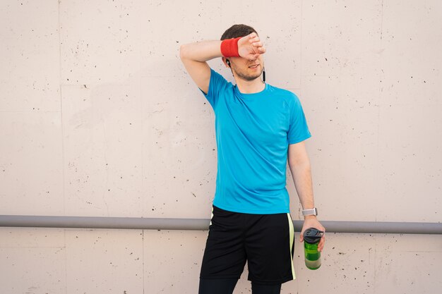 Tired athletic man wiping sweat on his forehead