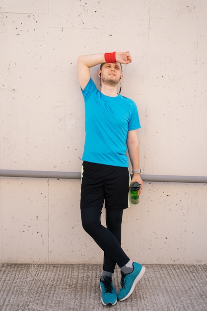 Tired athletic man wiping sweat on his forehead