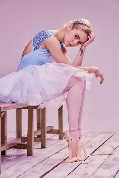 Tired ballet dancer sitting on the wooden floor