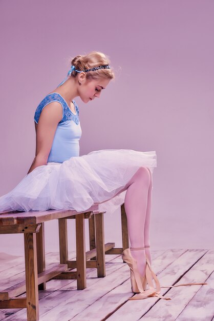 Tired ballet dancer sitting on the wooden floor