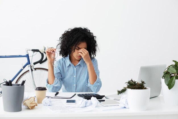 Tired black woman with glasses in hand rubbing eyes, full of sad restless thoughts