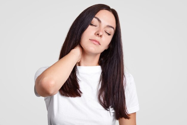 Уставшая брюнетка чувствует боль в шее, ведет малоподвижный образ жизни, нуждается в физической нагрузке, закрывает глаза, хочет спать