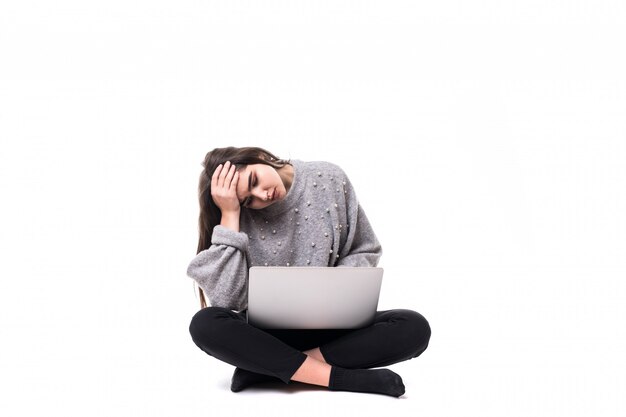 Tired Brunette girl model in grey sweater sit on the floor and work studie on her laptop