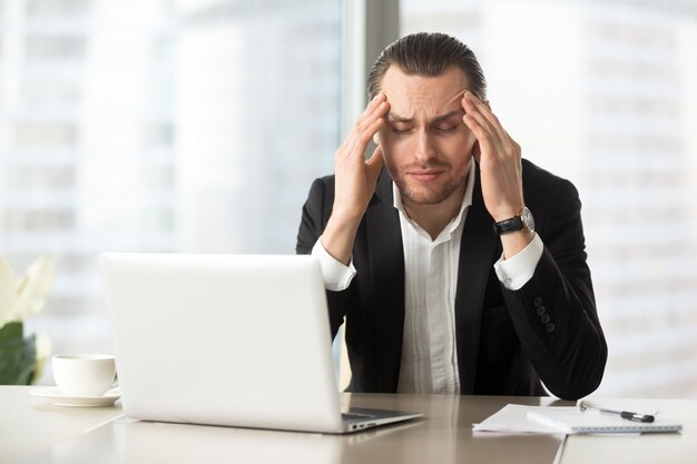 Утомленный бизнесмен страдая от головной боли