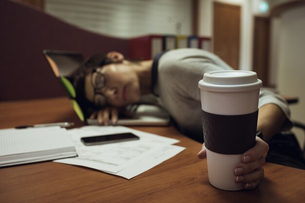 Tired businesswoman leaning on desk