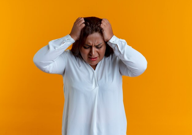 Tired casual caucasian middle-aged woman grabbed head isolated on yellow wall