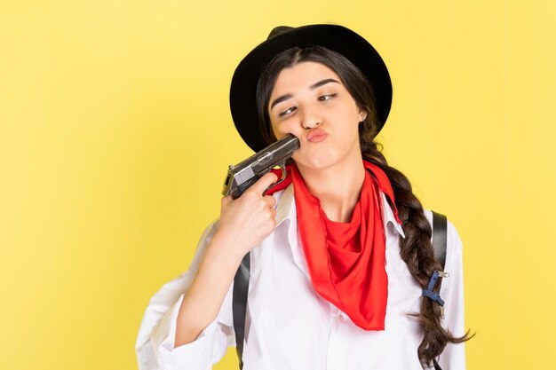 Tired cowgirl point gun herself on yellow background High quality photo