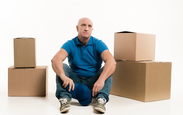 Tired delivery man posing with cardboard boxes