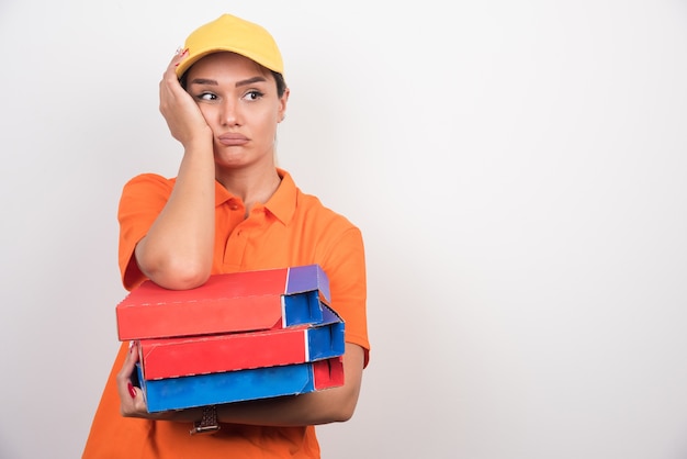 Tired delivery woman holding pizza boxes.