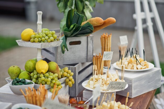 Tired dish with lemons and grape stands on table with cheese