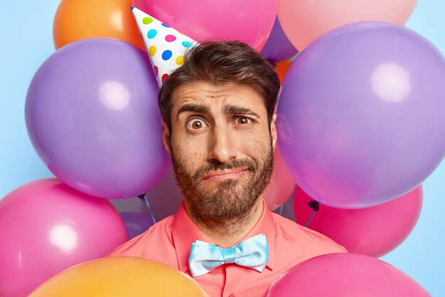 Foto gratuita artista di intrattenimento dispiaciuto stanco alla festa per bambini, indossa un cappello di compleanno