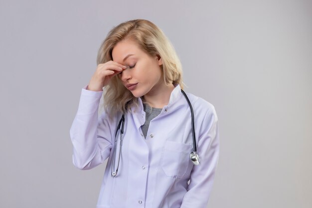 Усталый доктор молодая девушка со стетоскопом в медицинском халате положила руку на лоб на белом фоне