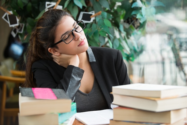 Tired female student sleeping at table with books