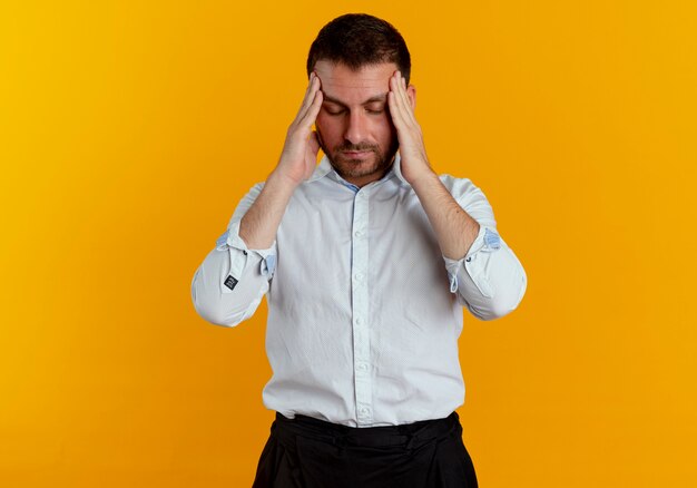 Foto gratuita uomo bello stanco tiene la testa guardando in basso isolato sulla parete arancione