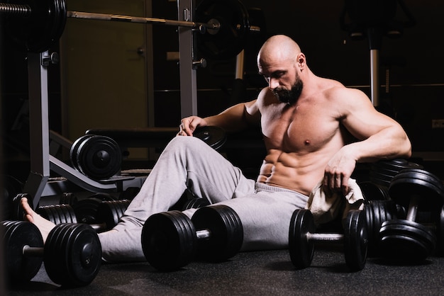 Free photo tired man amidst dumbbells