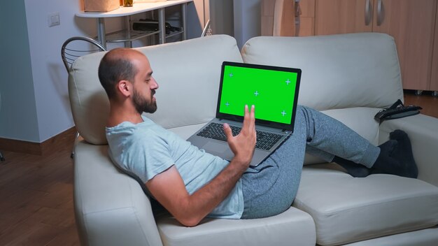 Tired man sitting on sofa while browsing marketing information using laptop computer