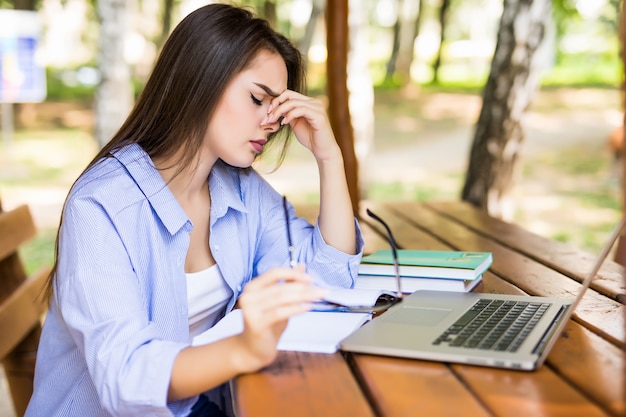 Tired manager using a laptop in a park table in the end of the day