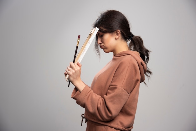 Tired painter holding paint brushes and canvas