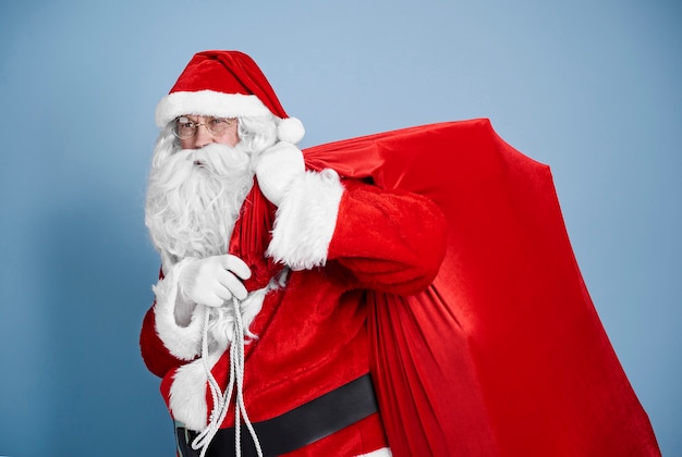 Усталый Санта-Клаус, несущий тяжелый мешок