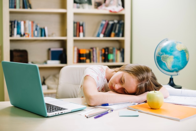 Free photo tired schoolgirl sleeping at table