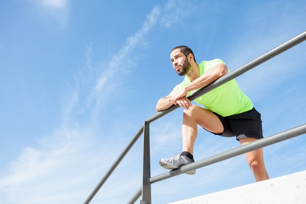 Tired Strong Man Relaxing and Leaning on Railing