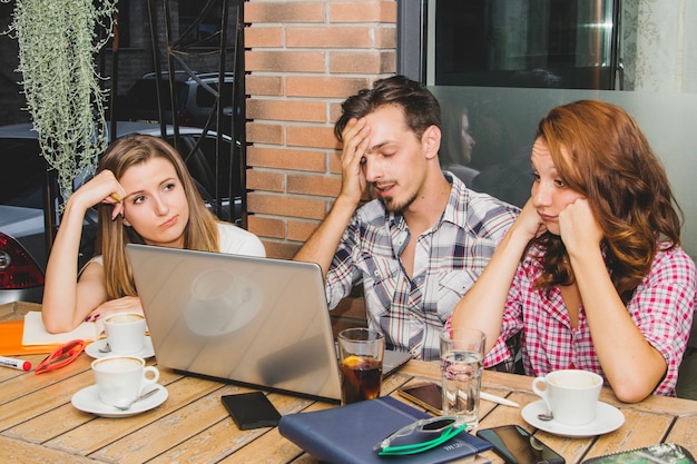 Tired students with laptop in cafe