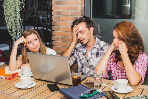 Tired students with laptop in cafe