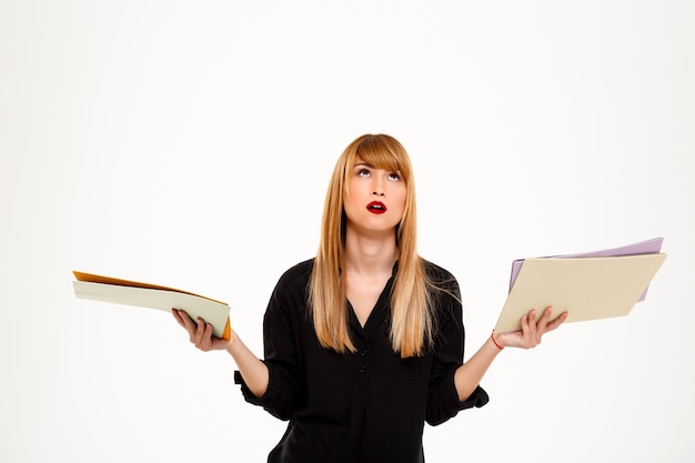 Free photo tired successful businesswoman holding folders over white wall