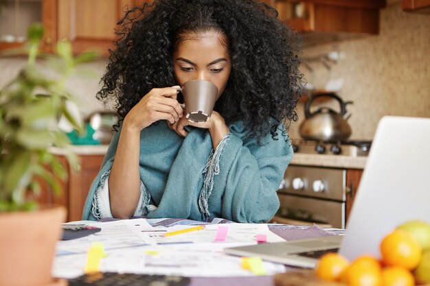 コーヒーをもう一杯飲んで疲れて不幸な若いアフリカ系アメリカ人女性