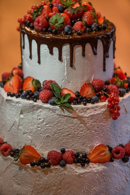 Tired wedding cake covered with white glaze, dark chocolate and