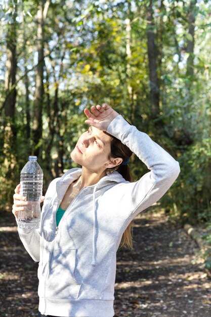 Tired woman drinking water and wiping her sweat