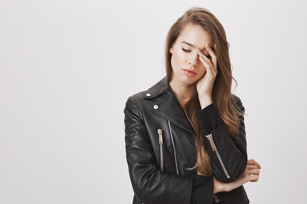 Tired woman in leather jacket, look down, facepalm upset