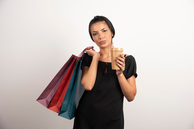 Tired woman looking at cup of coffee on white wall.