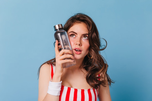 Tired woman puts cold bottle of water on her face