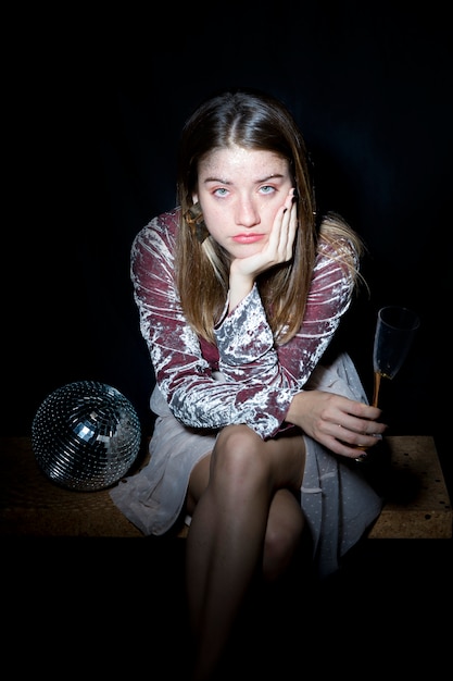 Tired woman sitting with champagne glass in hand