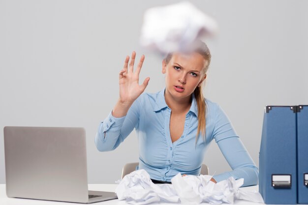 Tired woman throwing out office documents 
