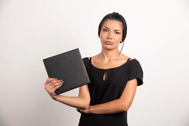 Tired woman with notebook looking at camera.